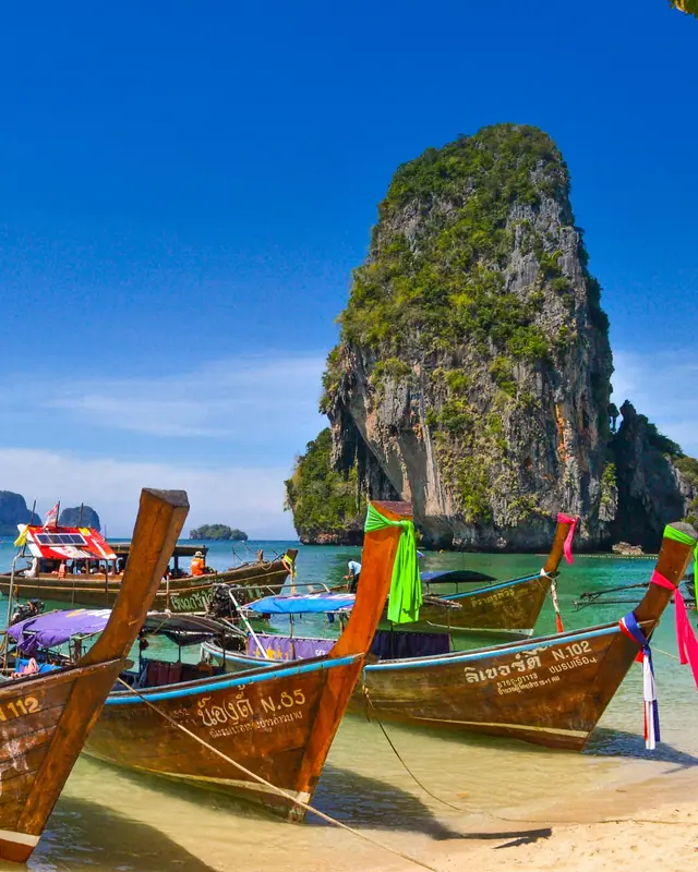 Longtail-Boote vor Kalkfelsen in Thailand